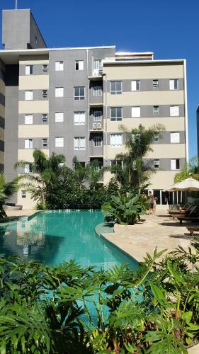 a swimming pool in front of a large building at Apartamento Resort Palmeiras 2 com 03 Quartos Ubatuba in Ubatuba