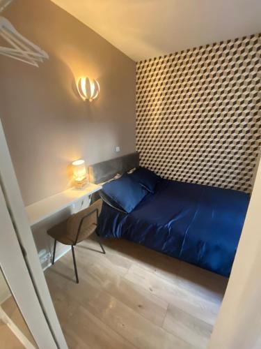 niewielka sypialnia z niebieskim łóżkiem i biurkiem w obiekcie Cosy courcelles w Paryżu