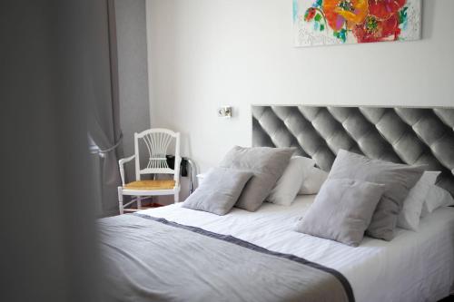 a bedroom with a large bed with white pillows and a chair at Hôtel Picardia in Saint-Valery-sur-Somme