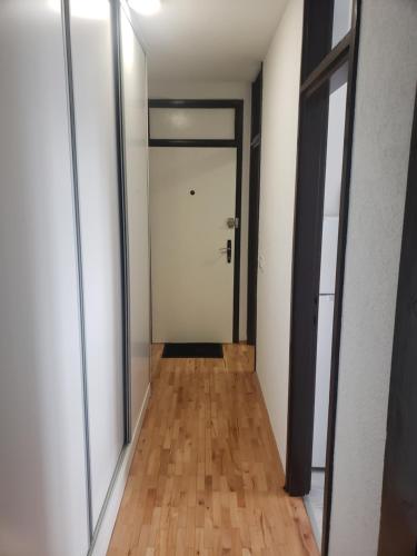 a hallway with a white door and a wooden floor at Stan na dan 50 BAM in Prijedor