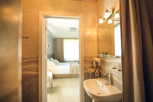 a bathroom with a sink and a toilet and a bed at Hotel Kera in Tbilisi City