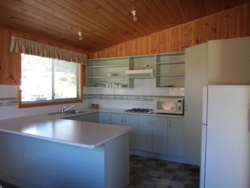 a kitchen with white appliances and a white refrigerator at Bicheno East Coast Holiday Park in Bicheno