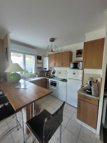 eine Küche mit weißen Geräten und einem Holztisch in der Unterkunft Le Papé logement meublé tourisme 3 étoiles in Villers-sur-Mer