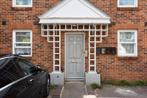 a brick house with a door and a car parked in front at Lancing Apartments - Spacious 2 Bed - Sleeps 6 - Burnham Village in Slough