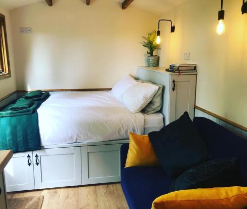 a bedroom with a bed and a couch in it at The Owls Rest Shepherds Hut Hethel in Norwich