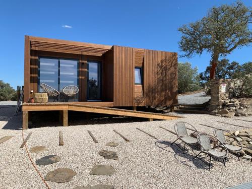 uma pequena casa de madeira com duas cadeiras no chão em Monte Clérigo Casas de Campo em Almodôvar