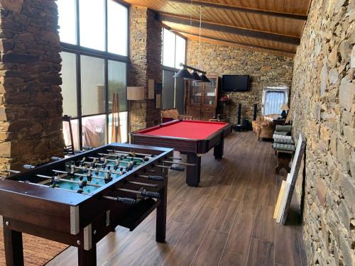 Habitación con 2 mesas de ping pong y pared de piedra. en Monte Clérigo Casas de Campo en Almodôvar