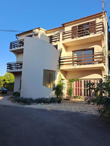 - un bâtiment blanc avec un balcon sur le côté dans l'établissement Apartmani Svitlana, à Sukošan