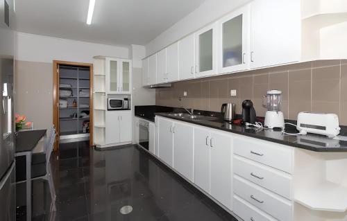 a kitchen with white cabinets and a black counter top at Praia Mar (sea view) by STAY Madeira Island in Ponta do Sol