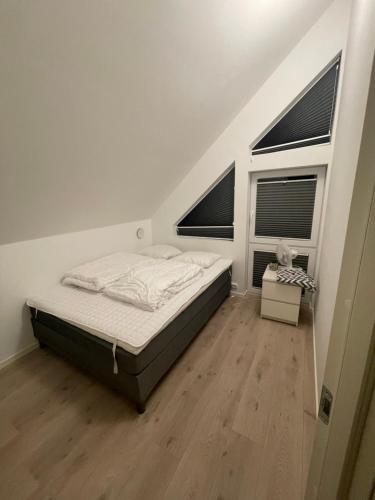 a white bedroom with a bed and two windows at Barnevennlig feriehus ved sjøen in Kristiansand