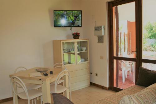 a living room with a table and a tv on the wall at Verdemare Sardegna Due Villette in Villasimius