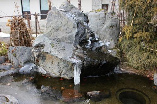 a water fountain in front of a large rock at Biei Shirogane Onsen AONOBI YUYU in Biei