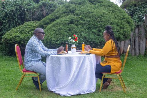 Un uomo e una donna seduti a un tavolo di The Nest Guest House a Kericho