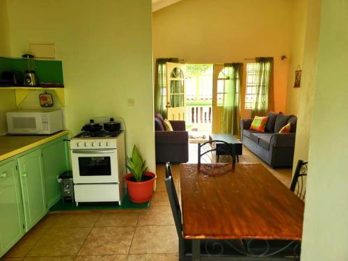 a kitchen and living room with a stove and a table at Juju's Cottage with magnificent views in Laborie