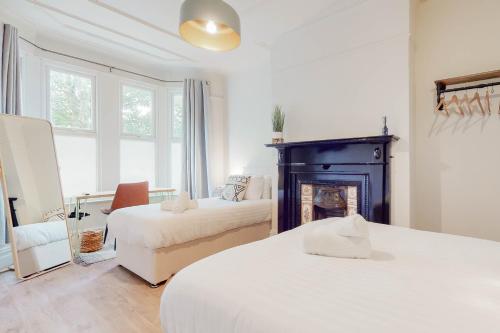 Habitación blanca con 2 camas y chimenea en Air Host and Stay - Lancefield House sleeps 15, 5 bedrooms 3 bathrooms, en Walton on the Hill