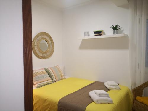 a bedroom with a yellow bed with towels on it at Casa Riera * En el centro de Oviedo, terraza, 2Hab in Oviedo