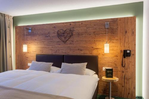 a bedroom with a large bed with a wooden wall at Hotel Jägerhof in Zermatt
