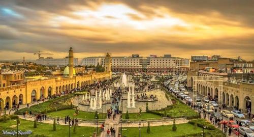 a city with a fountain in the middle of a street at Syros Hotel Erbil City Center in Erbil