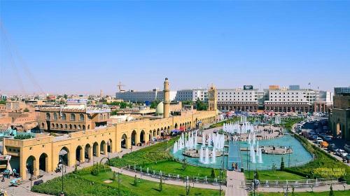 una città con una fontana di fronte a un edificio di Syros Hotel Erbil City Center a Erbil