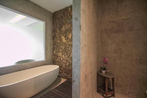 La salle de bains est pourvue d'une baignoire et d'une fenêtre. dans l'établissement Queen at Gunung Sari, à Ubud
