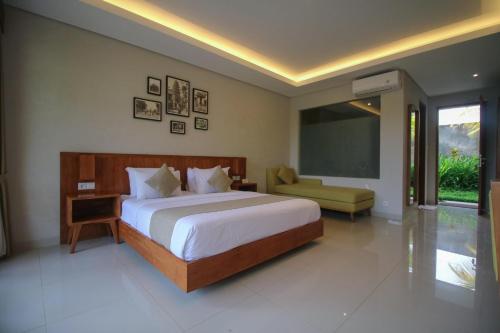 a bedroom with a bed and a chair and a chalkboard at Queen at Gunung Sari in Ubud
