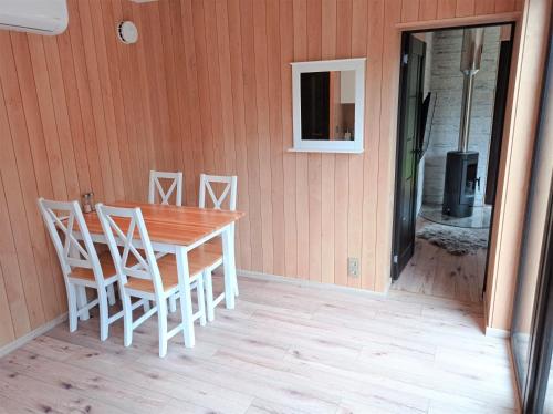 einen Holztisch und Stühle auf einer Veranda mit einem Fenster in der Unterkunft Roheluse metsamaja with hot tub and sauna 