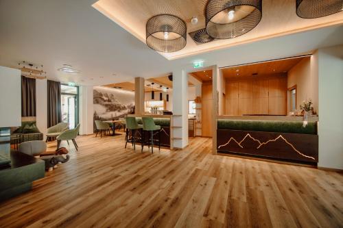 ein Wohnzimmer mit Holzböden und grünen Stühlen in der Unterkunft Hotel Salzburger Hof in Dienten am Hochkönig