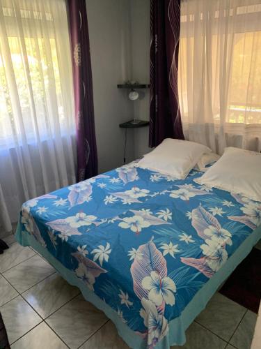a bed with a blue blanket with flowers on it at Matatia in Punaauia