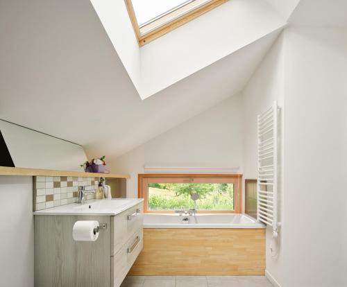 y baño con lavabo y bañera. en The wood house/La Maison Bois, en Montembœuf