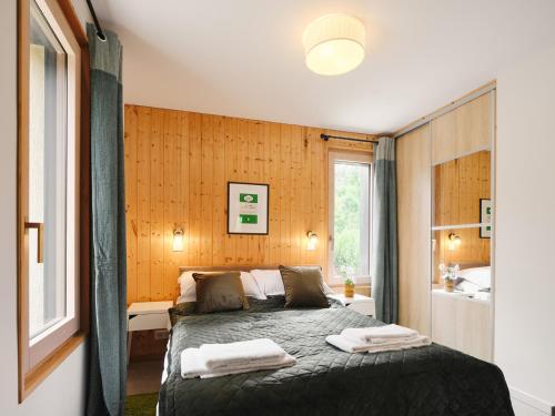 1 dormitorio con 1 cama con 2 toallas en The wood house/La Maison Bois, en Montembœuf