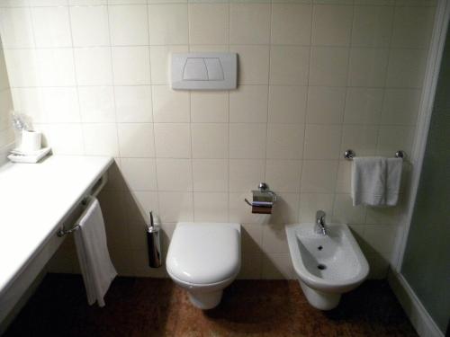 a white bathroom with a toilet and a sink at Hotel Corone in Caerano di San Marco