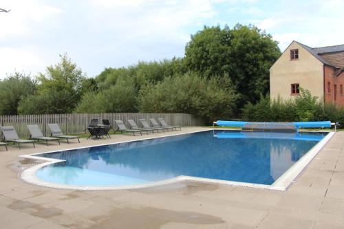 a swimming pool with chairs and a table in a yard at Coot Cottage in Somerford Keynes