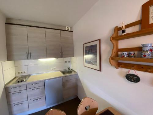 una pequeña cocina con armarios blancos y fregadero en Ferienwohnung 7 Bergschlößl Oberaudorf en Oberaudorf