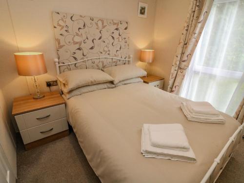 ein Schlafzimmer mit einem weißen Bett mit zwei Lampen und einem Fenster in der Unterkunft Number 15 in Carnforth