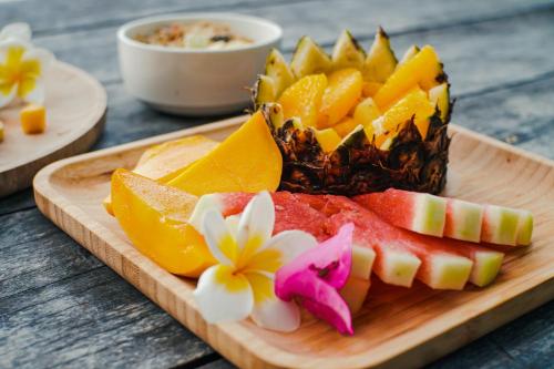 a plate of fruit on a cutting board with a pineapple at Sangat Island Dive Resort in Coron