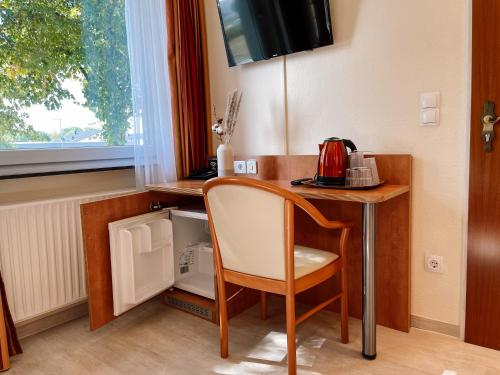 a desk with a chair and a microwave in a room at Hotel Falk in Bremen