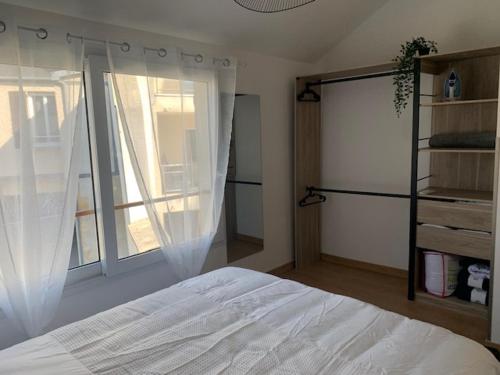 een slaapkamer met een wit bed en een raam bij Maison face à la Cathédrale in Bourges