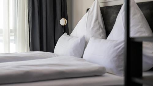 a bed with white sheets and pillows next to a window at Hotel Metropol in Tübingen
