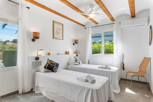 two beds in a room with white walls and windows at Villa Reva - PlusHolidays in Calpe