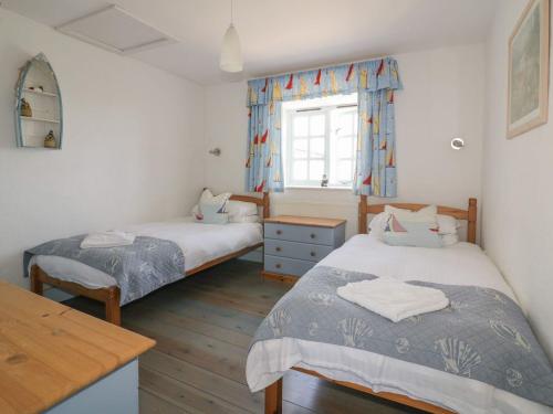 a bedroom with two beds and a desk and a window at Owls Roost in Saint Goran
