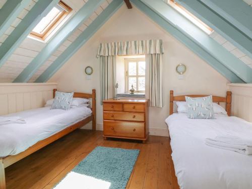 een slaapkamer op zolder met 2 bedden en een raam bij Dovecote in Saint Goran