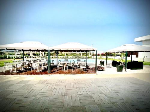 a patio with tables and chairs under umbrellas at Villa Giadel in Menfi