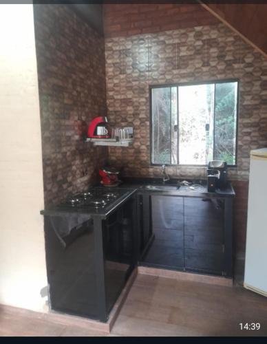 a kitchen with a black stove and a window at Chalé 3- Recanto Shambala in São Thomé das Letras