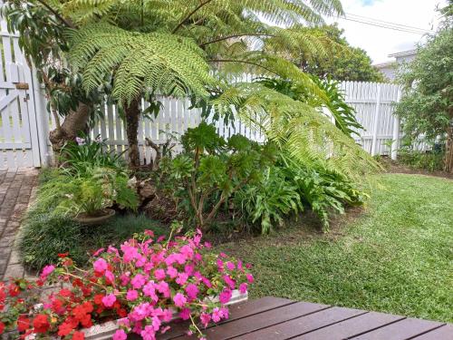 a garden with pink flowers and a white fence at Birdsong in Hermanus