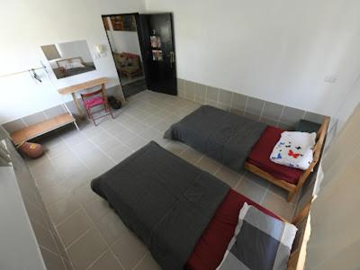 a bedroom with two beds and a table and a desk at St.Jadoor Inn in Al Azraq ash Shamālī