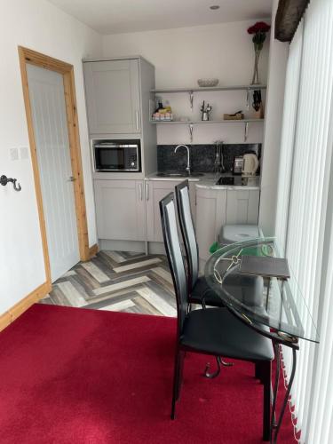 małą kuchnię ze szklanym stołem i krzesłami w obiekcie The Canteen Beautiful 1-Bed Apartment in Keswick w mieście Threlkeld