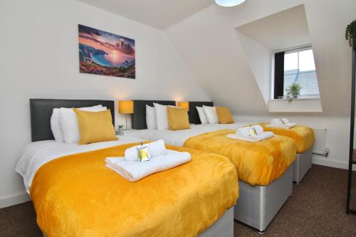 two beds in a room with yellow sheets at Serene 7Bed Escape - Steps from Coventry City Center, Holiday Bliss! in Coventry