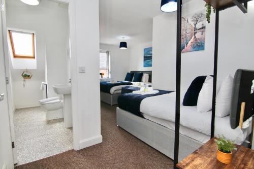 a hotel room with two beds and a bathroom at Serene 7Bed Escape - Steps from Coventry City Center, Holiday Bliss! in Coventry