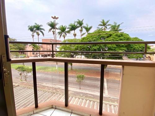 uma varanda com vista para uma rua e palmeiras em Apto no Parque dos IPES com 2 Quartos ArCond WiFi Fibra Home Office Garagem em Dourados em Dourados