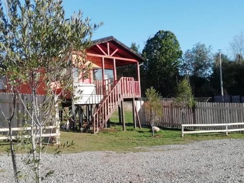 una pequeña casa con una estructura roja junto a una valla en Adilauquén Cabañas y Tinajas Calientes, en Puerto Varas